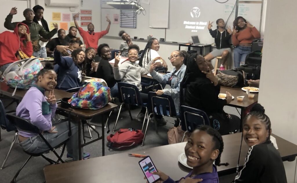 Group of students smiling and posing for a photo in a classroom setting.